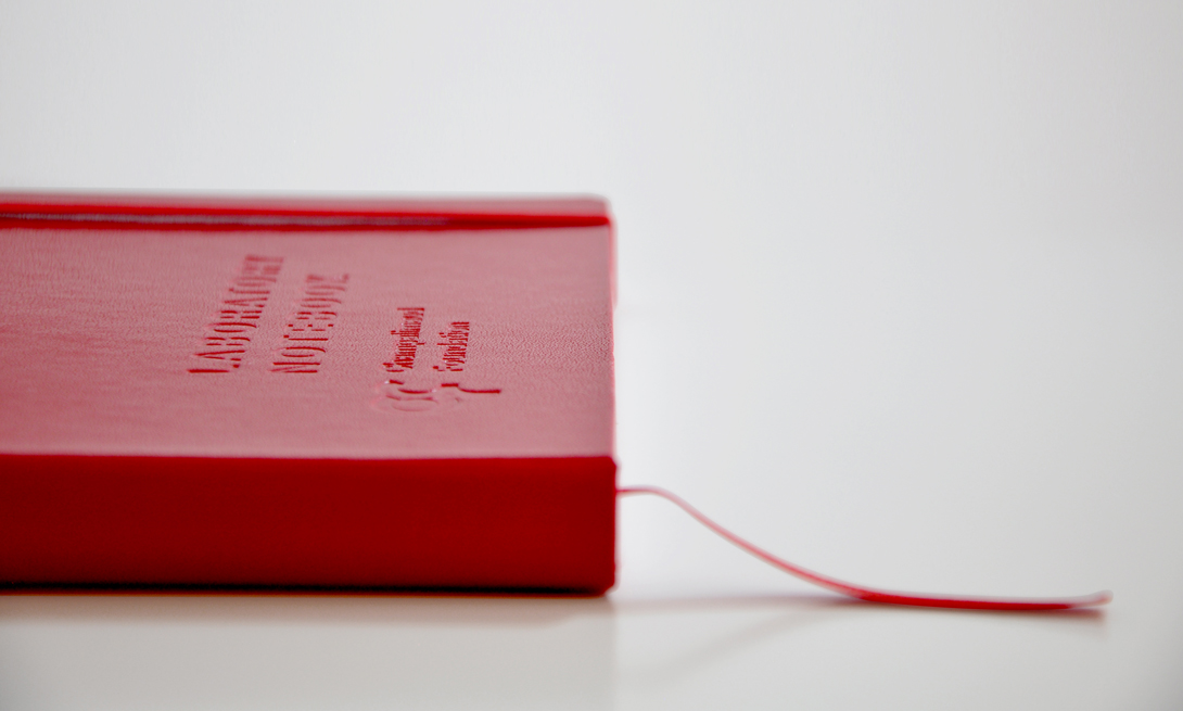 O LabBook da instituição fechado, mostrando a capa dura e o design robusto do livro de registo de experiências de laboratório.